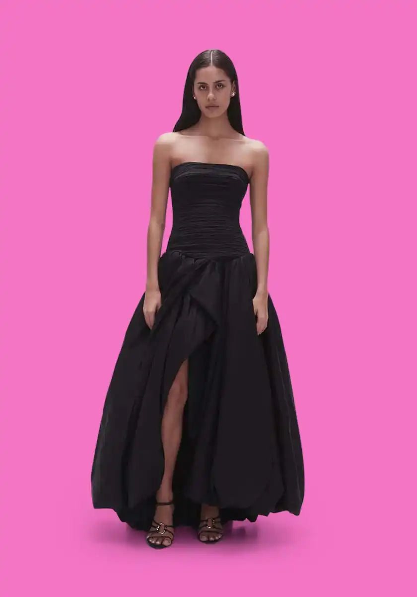 A woman in a strapless black ball gown with a thigh-high slit.