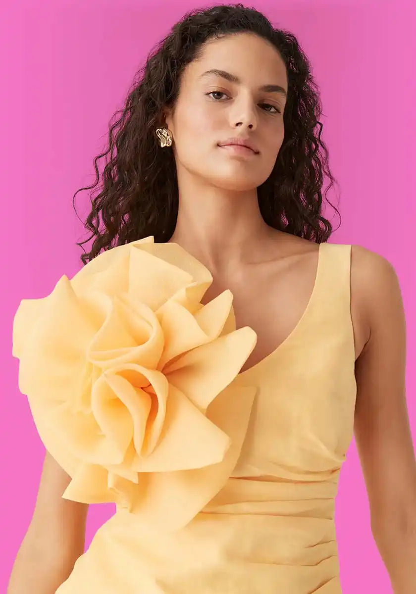 Woman in yellow dress with floral embellishment.