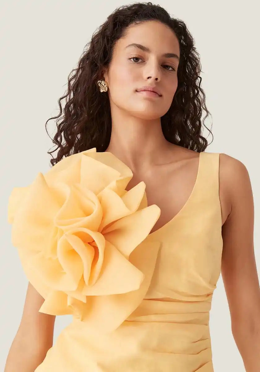 Woman in yellow dress with flower detail.